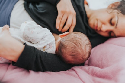 mom nursing baby while lying down on bed in article about combination feeding breast milk and formul...