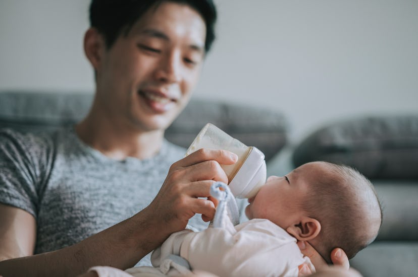 Young asian father feeding his newborn baby with bottle in article about combination feeding breast ...