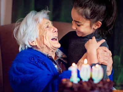 Great-grandmother is hugging her great-granddaughter at her 100th birthday