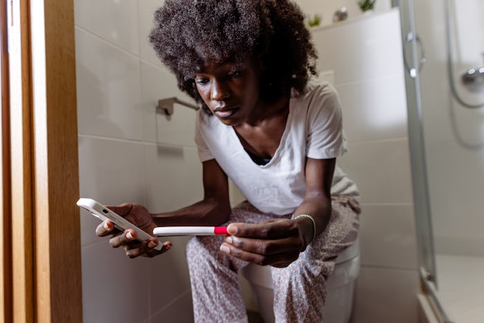A woman is sitting on her toilet bowl at home. She is ready to make a phone call to discuss the resu...