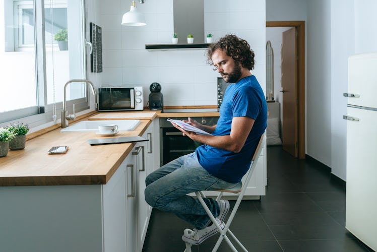 Man in kitchen looking at bills