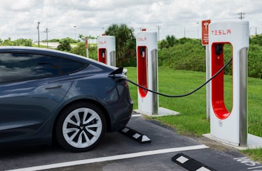 Tesla Model Y electric car at Tesla Supercharger charging station. The charging station and grey Tes...