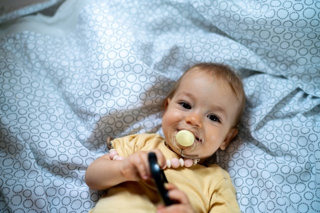 High angle view of cute baby girl lying on the bed and looking at camera