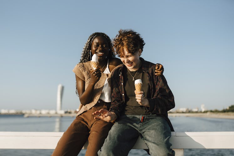 two friends enjoy ice cream on a pier as they consider how the May 2023 black moon will affect their...