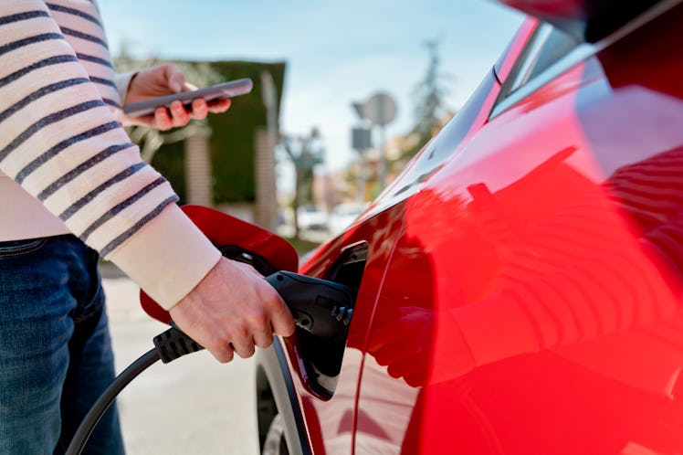 A person plugging in the charger for their electric vehicle.