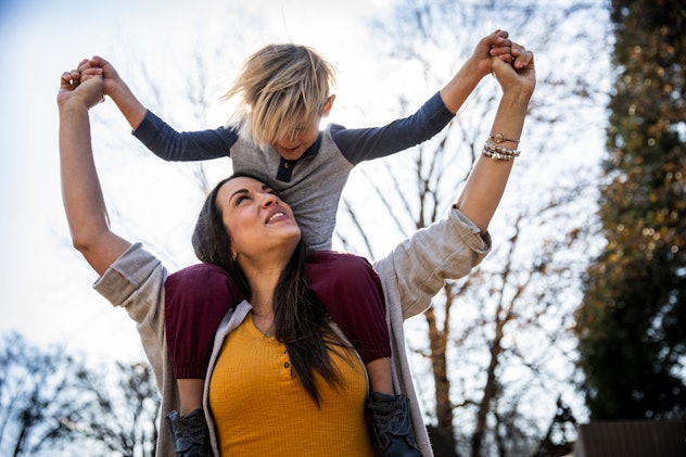 Young boy riding on mother's shoulders outdoors, in a list of Mother's Day jokes 