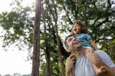 Brazilian father and son looking very happy playing at the park and carrying the boy on shoulders