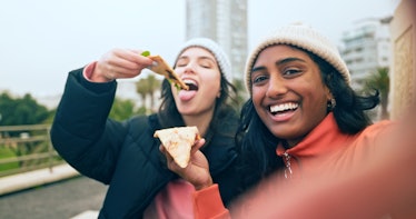two friends enjoy pizza together as they take a selfie and consider how the May 2023 black moon will...