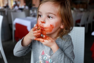  A three year old girl eating home made pasta in a restaurant in The Piazza del Campo in Siena, Ital...