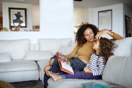 A mom and daughter sit on the couch reading children's books about depression.