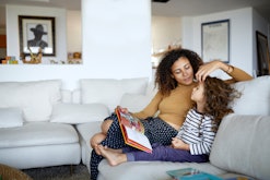 A mom and daughter sit on the couch reading children's books about depression.