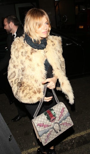Sienna Miller wears a fuzzy coat and carries a Gucci Dionysus bag. 