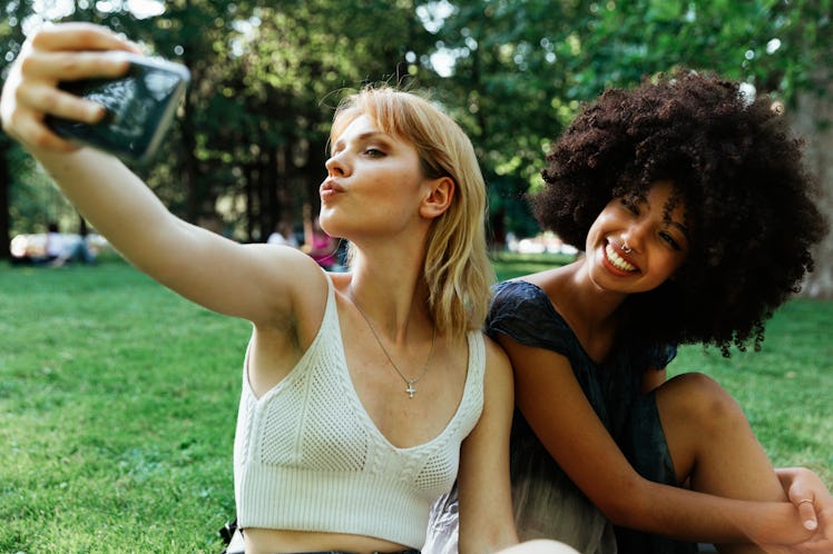 two friends pose for a selfie during a picnic as they think about how their zodiac signs will be the...