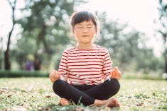best yoga poses for kids for anxiety; Lovely little girl in closed eyes sitting with crossed legs wh...