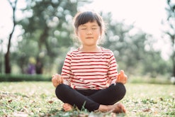 best yoga poses for kids for anxiety; Lovely little girl in closed eyes sitting with crossed legs wh...