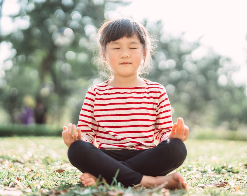 best yoga poses for kids for anxiety; Lovely little girl in closed eyes sitting with crossed legs wh...