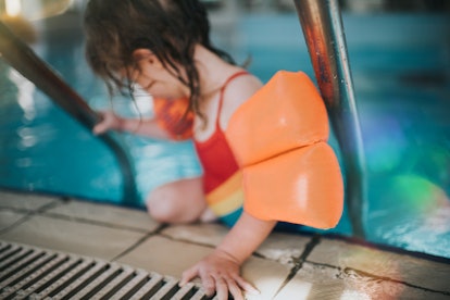 Little girl wears water wings in a story about how to choose the best life jacket for kids.