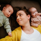 A mom lays on the ground with her twin babies. The SSA just released the top baby names of 2022. 