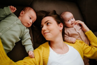 A mom lays on the ground with her twin babies. The SSA just released the top baby names of 2022. 