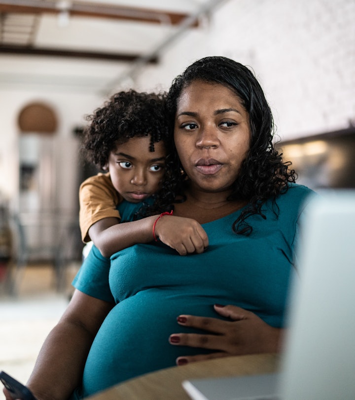 Pregnant woman using laptop at home with son, having a little uneasy feeling before labor. 