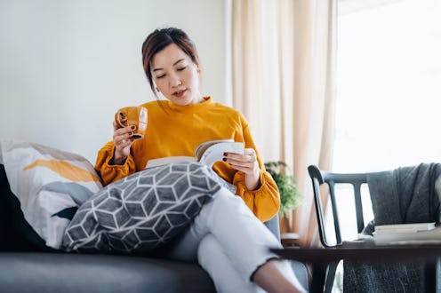 Beautiful young Asian woman reading a book while drinking a cup of coffee. Enjoying a quiet time and...