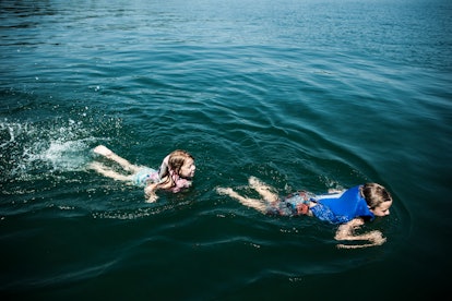 Children wearing kids' life jackets while swimming in a lake, in a story about how to choose the bes...