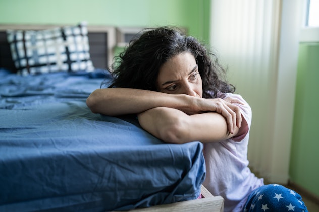 Mid adult woman sitting home alone, worried that she has rejected child syndrome