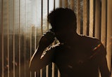 Silhouette of an unknown man on a phone against window blinds in article about rage disorder
