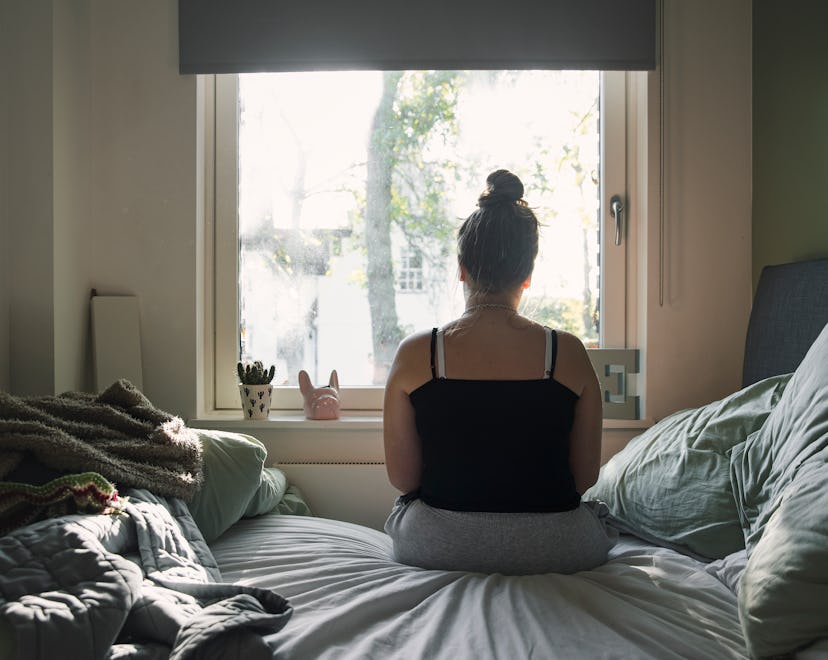Do I have a mental health issue or PMS? Woman sits on bed looking out window with her back to camera...