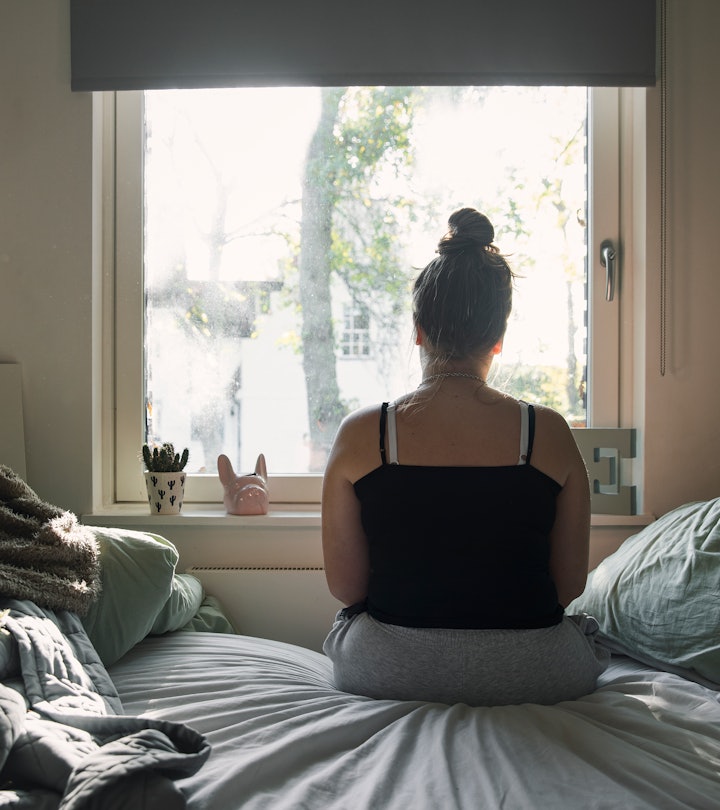 Do I have a mental health issue or PMS? Woman sits on bed looking out window with her back to camera...