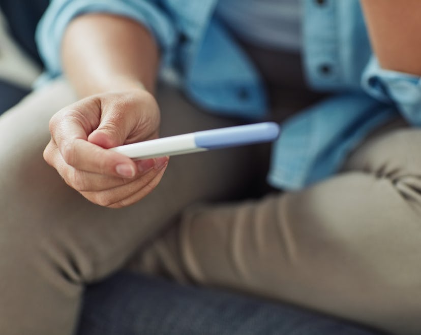 Cropped shot of a young woman holding a pregnancy test at home, worrying about miscarriage