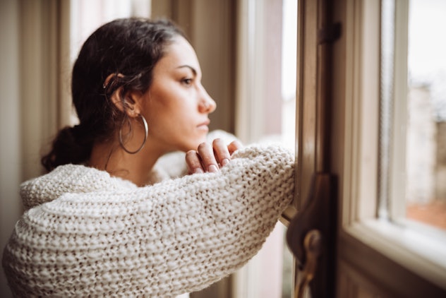 pensive woman in front of the window, experiencing rejected child syndrome