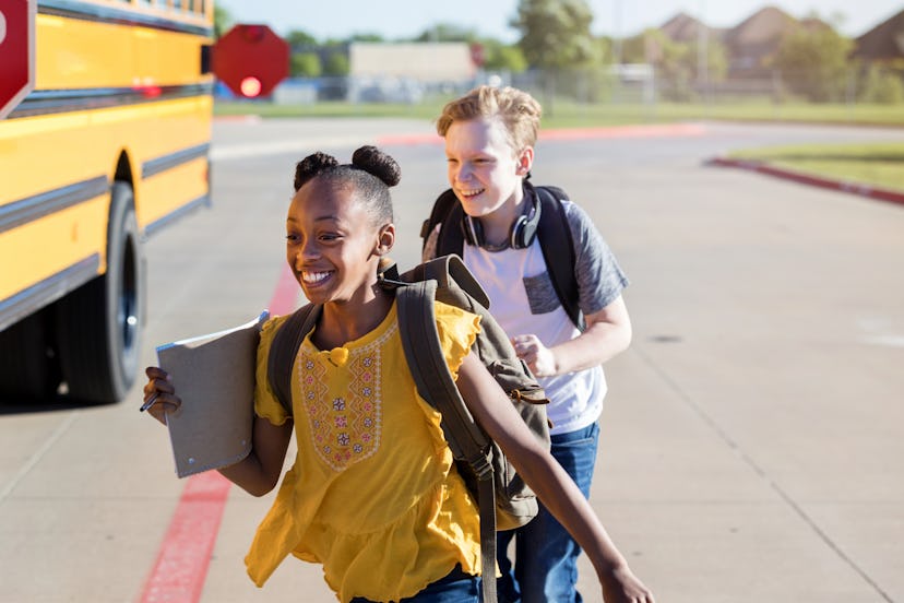Two junior high students race each other to the school bus to make it on the bus before it leaves on...