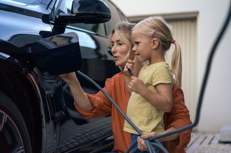 Mother and daughter refueling electric car