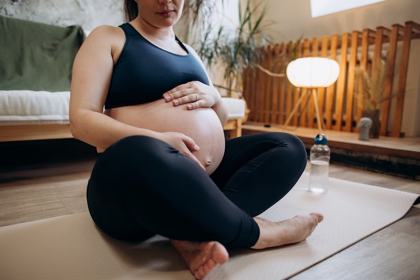 Close-up beautiful Caucasian future mother in sports clothes enjoying doing yoga. pelvic rest.