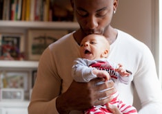 black father kissing newborn's head in article about best gifts for new dads