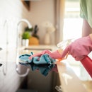 Close up of a young woman using cleaning products to clean the kitchen in her home