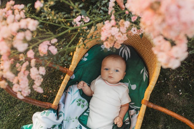 May baby names like Hunter would fit this newborn boy lying in vintage baby wicker cot looking up at...
