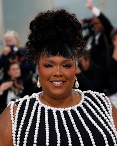 A portrait photo of Lizzo at the 2023 Met Gala wearing a pearl-encrusted dress. 