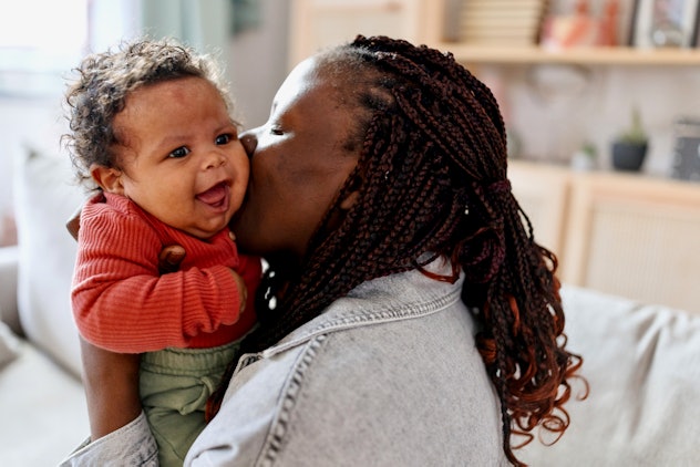 Spooky baby names would fit this baby, giggling as she gets a kiss from Mom.