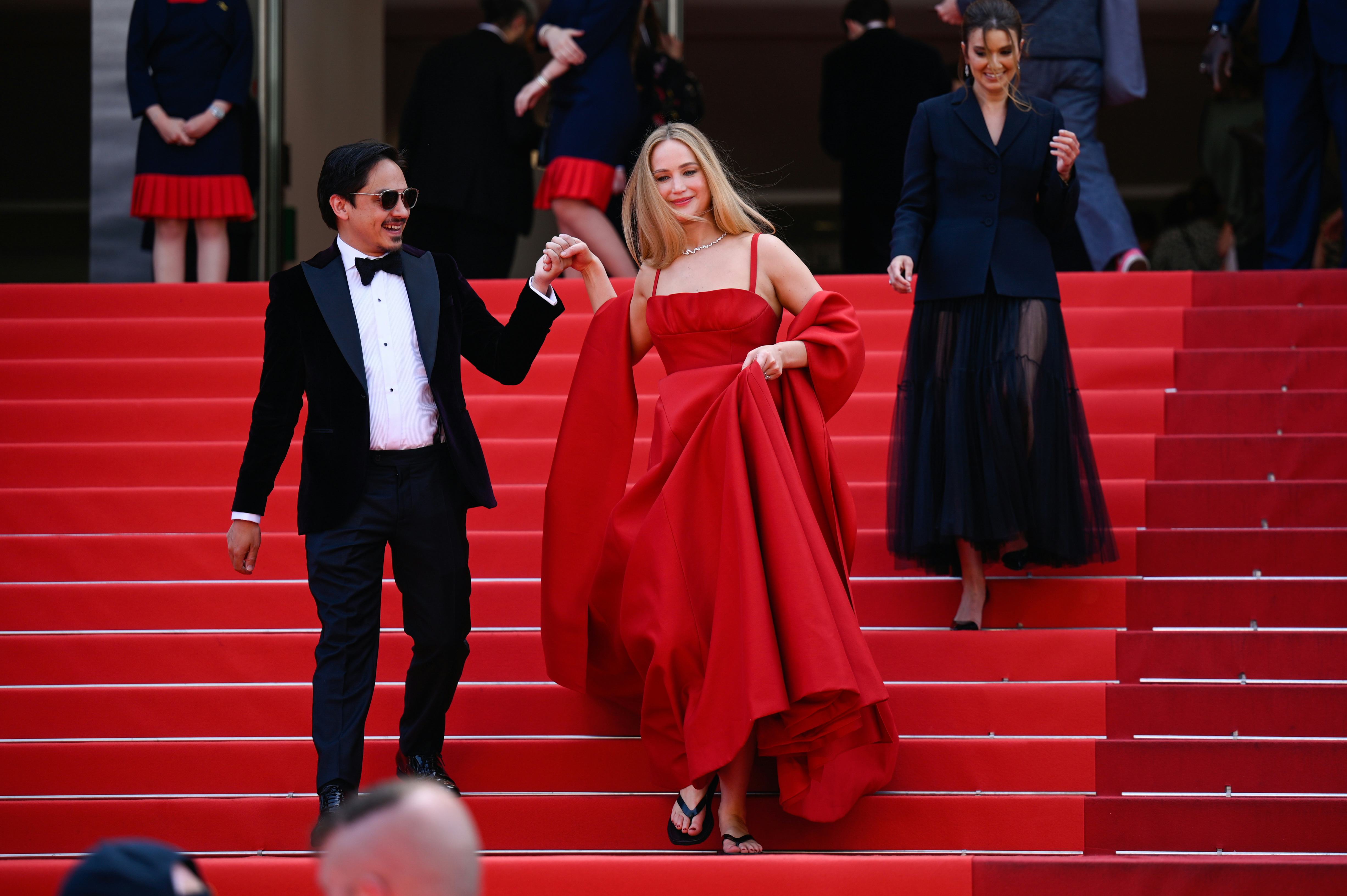 Jennifer Lawrence wears a sleeveless red gown while being escorted down at the &ldquo;Anatomie D&rsquo;une Chute&hellip;