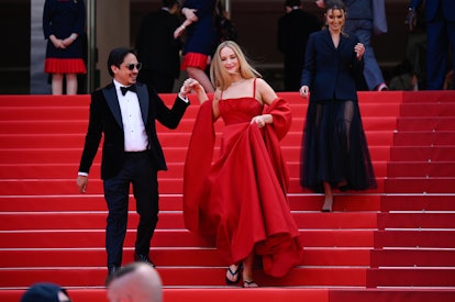 Jennifer Lawrence wears a sleeveless red gown while being escorted down at the "Anatomie D'une Chute...