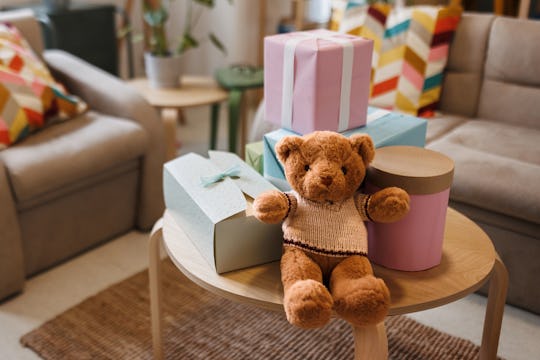 Teddy bear with gifts arranged on coffee table for baby shower party with no people