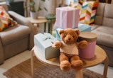 Teddy bear with gifts arranged on coffee table for baby shower party with no people