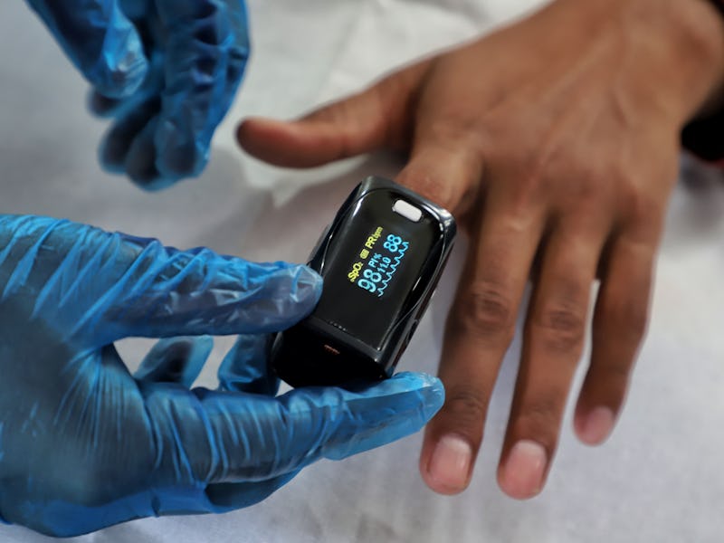 A Health worker uses Oximeter to check the Oxygen Level of a Person at a School Turned COVID-19 Cent...
