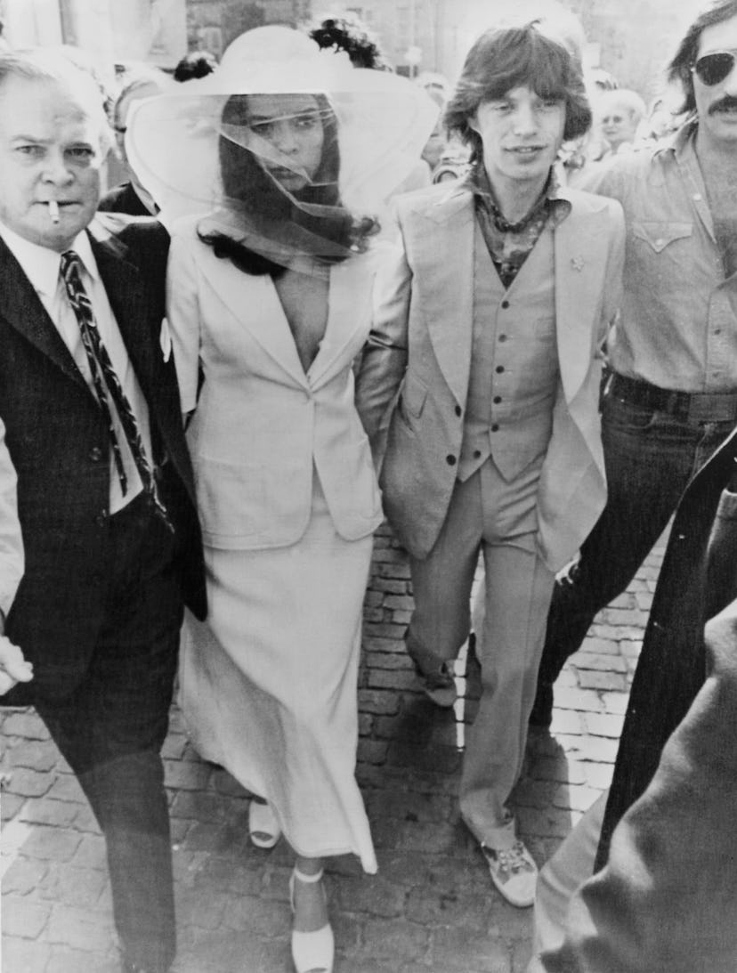 Bianca Jaggers wears a bridal skirt suit with a veiled wide-brimmed hat to marry Mick Jagger. 