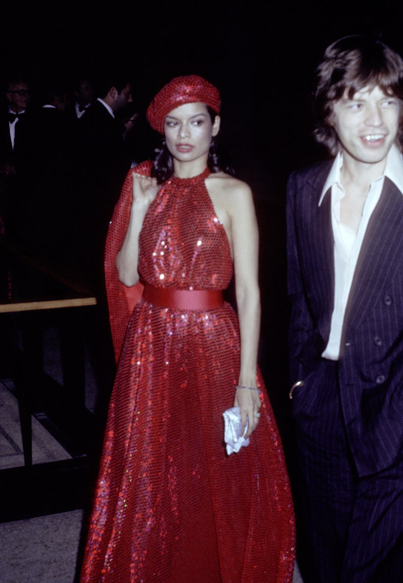 Bianca Jagger wears a red sequined Halston dress to attend the 1974 Met Gala with Mick Jagger. 