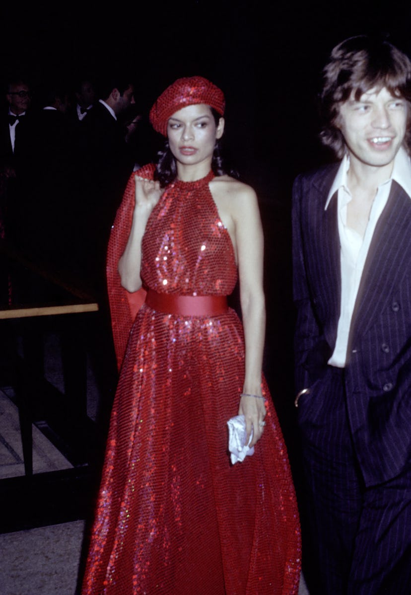Bianca Jagger wears a red sequined Halston dress to attend the 1974 Met Gala with Mick Jagger.