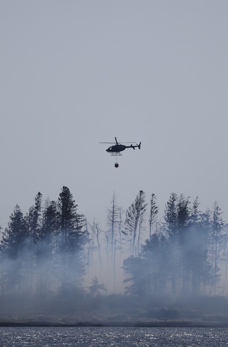 CAPE ELIZABETH, ME - APRIL 14: A helicopter prepares to douse a controlled burn on Richmond Island t...