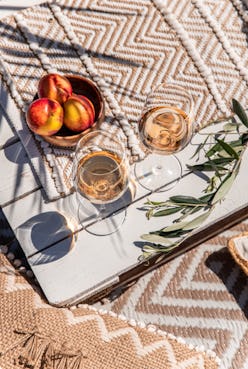 Drinking rose wine glasses on white wood table with peaches on sunny mediterranean day